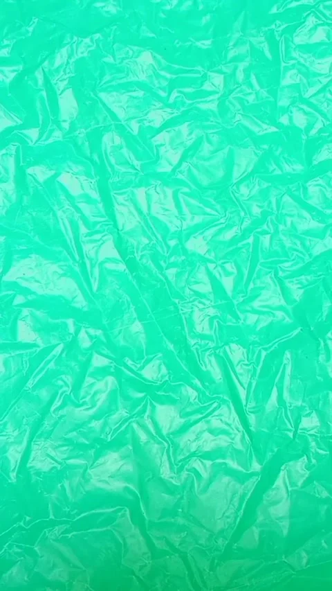 Green crumpled plastic bag texture background rotating. HDPE Polyethylene Video stock 316378595
