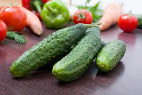 Green cucumbers on a background of different vegetables. Fresh vegetables Foto stock