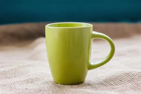 Green cup on the table by the window on sackcloth isolated, with a hot drink  Stock Photos