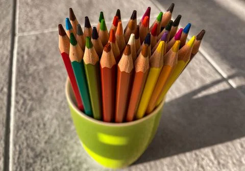 In a green cup, there is a bundle of multi-colored drawing pencils. Stock Photos