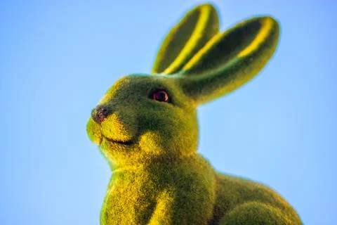 Green cute Easter bunny with long ears on background of clear blue sky in spring Stock Photos