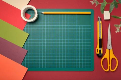 Green cutting mat surrounded by colored paper and craft tools on desk. Crea.. Stock Photos