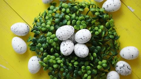 Green decorative Easter quail eggs wreath on yellow wooden table 動画素材 151118789