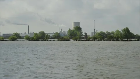Green Dike in Broad River Passing in Front of Large Factory Stock Footage 277359203