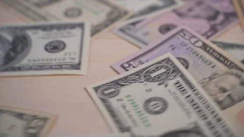 Green dollar bills slowly fall in a stack on a wooden background and spin Vidéo 147537968