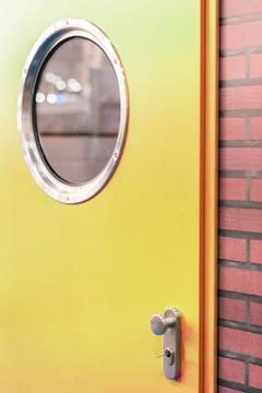 A green door with a round window in a brick wall Foto stock