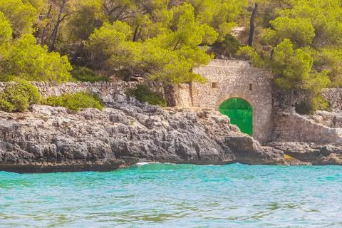 Green door in the stone wall turquoise beach Mallorca Spain.. Stock Photos
