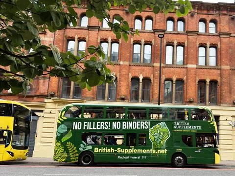 Green double decker bus with British Supplements advertisement parked on a .. Stock Photos