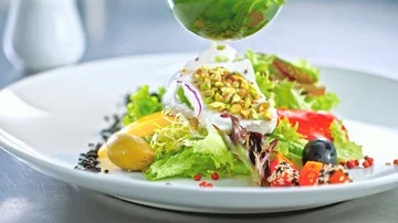 Green dressing pouring over mixed salad Видео 85602620