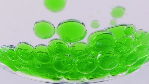Green drops of oil fall to the bottom of a glass bowl Vídeo Stock 258322444