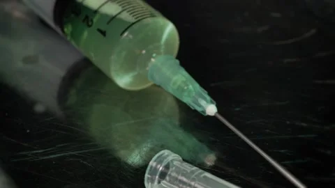 Green drug liquid inside a plastic syringe, rotating in a b-roll video shot Stock Footage 236785601
