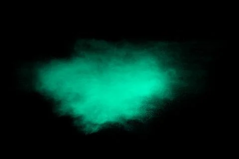 Green dust particles explosion on black background. Color powder dust splash. Stock Photos