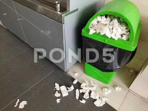 Green Dustbin contains overflow papers waste spread outside no proper ...