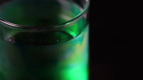Green Dye Diffusing in Water Glass Under Studio Lighting Stock Footage 318943053