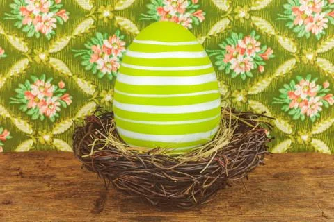 Green dyed big easter egg in a bird nest on a wooden table Stock Photos