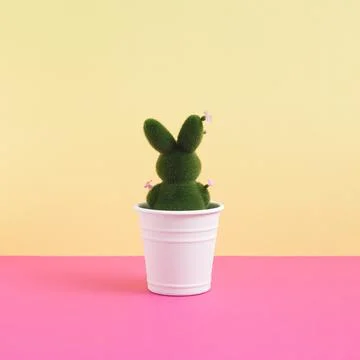 Green easter bunny decorated with flowers in flowerpot on yellow and pink Stock Photos