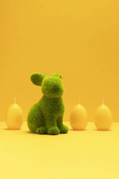 Green Easter Bunny, rabbit with three yellow candles of eggs shape on matching Stock Photos