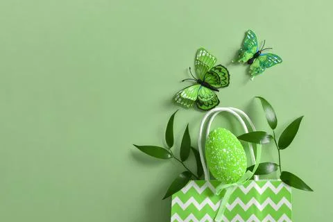 Green Easter egg butterflies and twigs in a paper eco-bag on a green backgrou Stock Photos