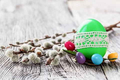 Green Easter egg decorated with lace and willow branch on wooden background Foto stock