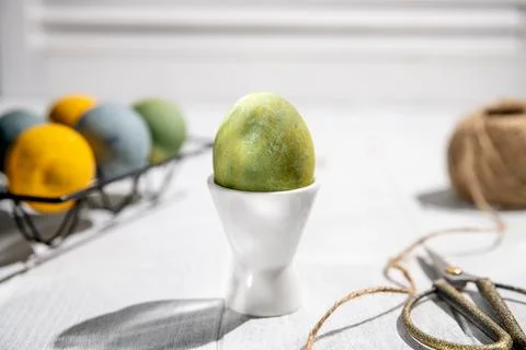 Green easter egg standing on a white egg cup on a white wooden table with o.. Stock Photos