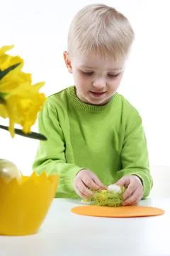 Green Easter - a little boy decorates Easter eggs  Stock Photos