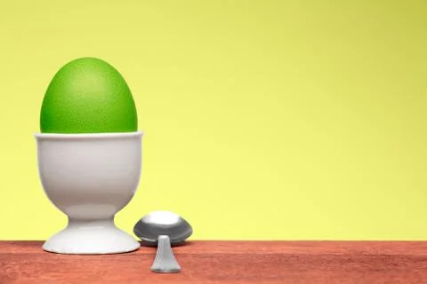 Green egg in white egg cup Stock Photos