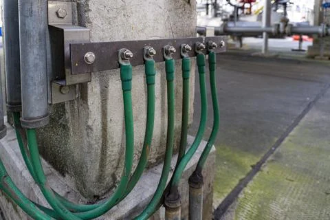 Green electrical cable is attached to a metal pole Stock Photos