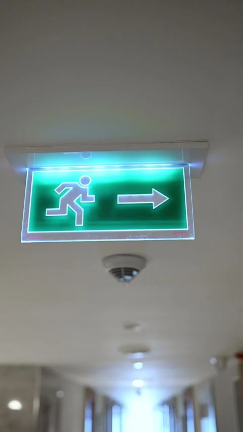 Green emergency exit sign with arrow glowing in the dark. Modern LED fire exit Stock Footage 333333577