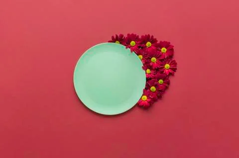 Green empty dish and red flowers. Eco-friendly platter. Stock Photos