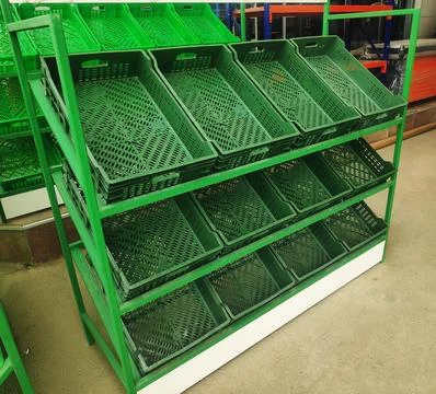Green empty plastic boxes are on the shelves for various products and fruit.. Stockfoto's
