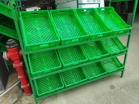 Green empty plastic boxes are on the shelves for various products and fruit.. Stock Photos