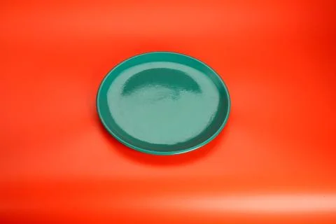 Green empty  plate on red table Stock Photos