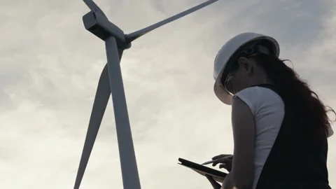 A green energy engineer studies the power and operation of a wind turbine that Stock Footage 249277475