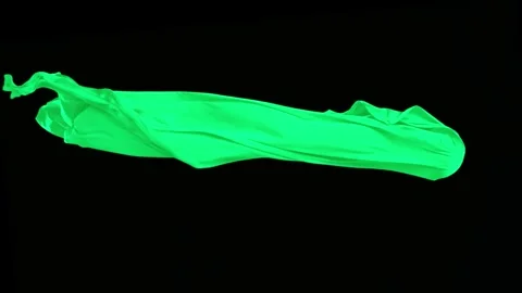 Green fabric flowing dynamically and elegantly against black backdrop Stock Footage 327570596