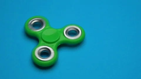Green fidget spinner on blue background Stock Footage 118986915
