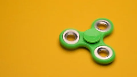 Green fidget spinner on yellow background Stock Footage 118987108