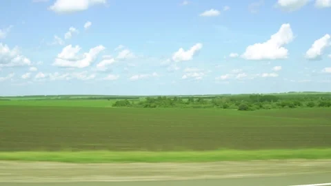 Green field and blue sky view from the window of a car driving on the highway Stock Footage 132814939