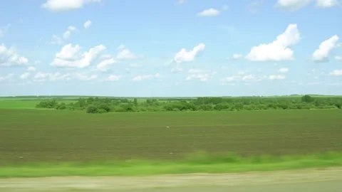 Green field and blue sky view from the window of a car driving on the highway in Stock Footage 133082508