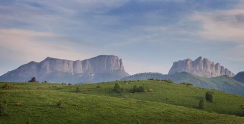 Green field on a background mountains (Eastern and Western Acheshbok) under a Stock Photos