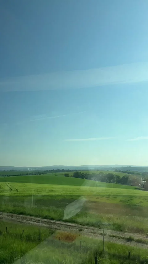Green field landscape observed from a moving vehicle, showcasing a vast natural Stock Footage 335813809