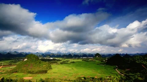 Green fields and mountains under a cloudy sky create a scenic landscape Stock Footage 311818680