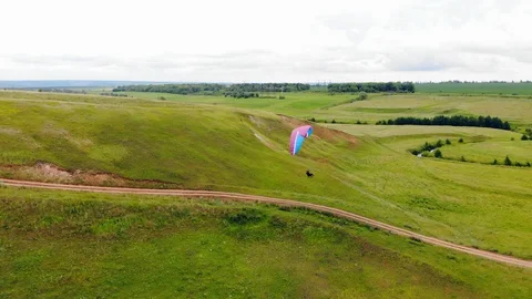 Green fields and a person doing paragliding along them. Extreme sport concept. Video stock 113515328