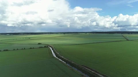 Green fields and sky and clouds with a small trench reflecting, aerial Stock Footage 165510109
