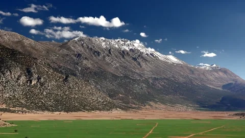 Green fields and snowy peaks in Bey Mountains - Mountain Farms and Travel Scene Stock Footage 339561586