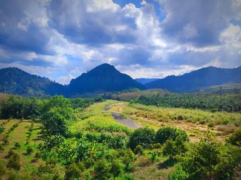 Green fields and a winding river in the mountains during a sunny day. Namto.. Stock Photos