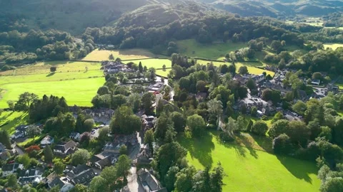Green fields embrace a quiet village nestled in hills Stock Footage 345528097