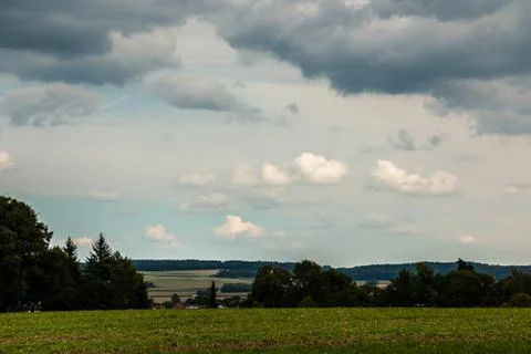 Green fields, green meadows, dark forests and the cloudy sky Stock Photos