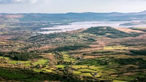 Green fields, rolling hills, and small houses span the valley as sunlight Stock Photos