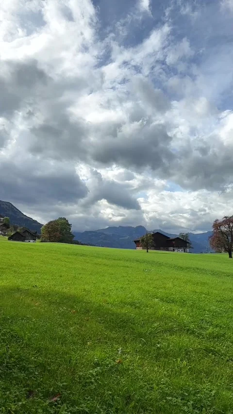 Green Fields with Rustic Houses and Mountain Backdrop. Stock Footage 289370723