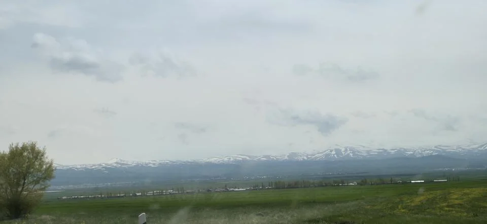 Green Fields with Snow-Capped Mountain Range Stock Photos